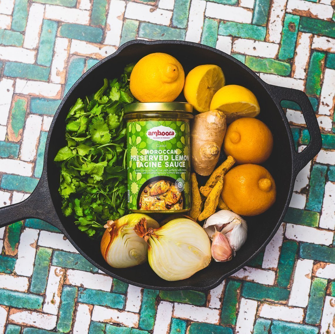 Amboora Moroccan Tagine Sauce in a jar in a pan surround with ingredients