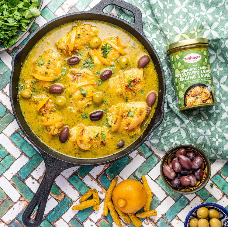 Amboora Moroccan Tagine Cooking Sauce in a jar with a cooked chicken tagine paired with olives
