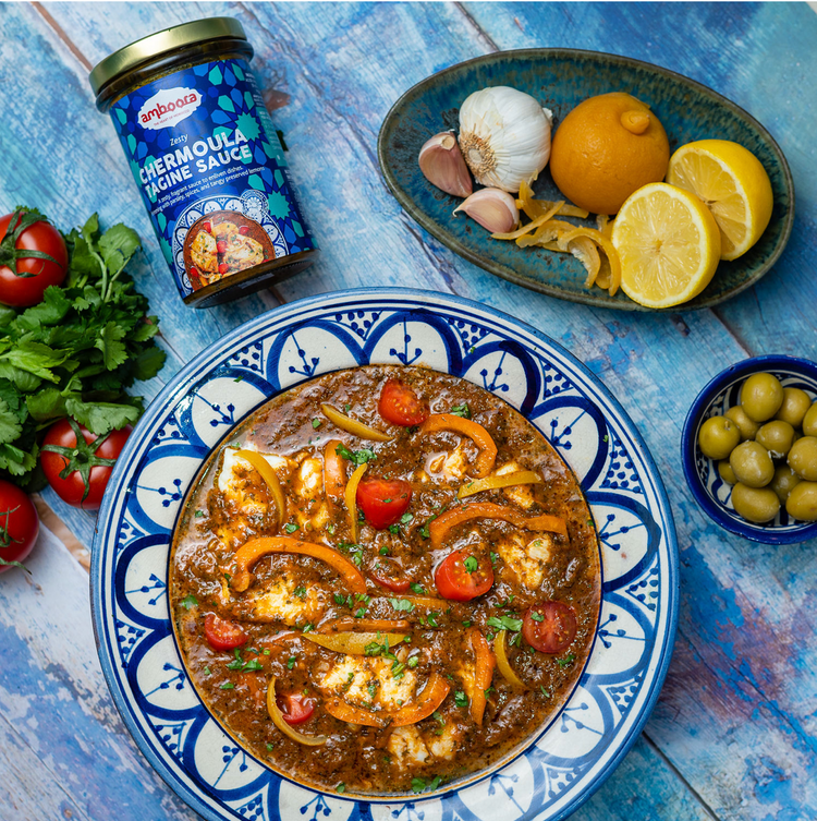 Amboora Moroccan Tagine Sauce in a jar with a cooked fish tagine paired with tomato and peppers